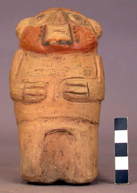 Pottery figurine -tan paint on body; brown paint on face; hands accross chest;