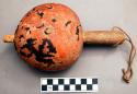 Gourd ceremonial rattle. Flattened shape, wooden handle. Paint on gourd worn o