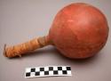 Crow dance rattle. Round hide head painted red with wrapped wood handle.
