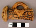 Figurine fragment with one arm akimbo; traces of red paint; black manganese pain