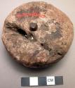 Round stone charm with piece of iron riveted through center (iron an old piece,