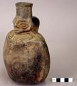Ceramic bottle, 1 strap handle, moulded human face and arms, rounded base