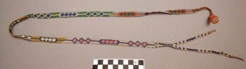 Beaded strip, possibly a hair ornament. Narrow band of beads.