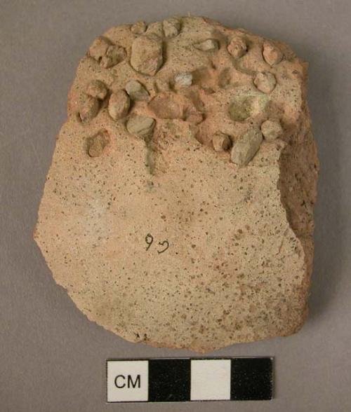 Rough, light colored potsherd ornamented with dabs of clay on the surface