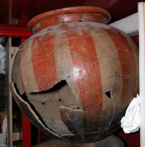 Ceramic partial jar, globular body, orange on buff, vertical stripes, mended.