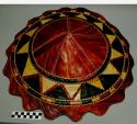 Large round basketry hat with scalloped edge. Red with yellow and +