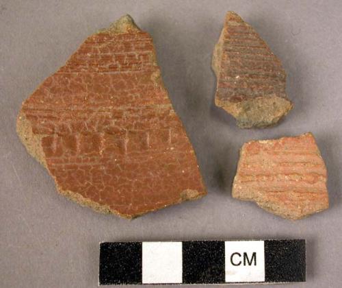 3 potsherds - dark red painted? outside; plain reddish inside; grooved decorated